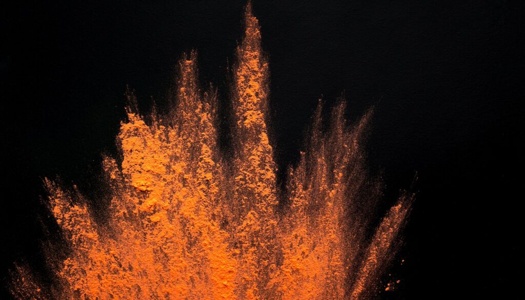 Abstract colored dust explosion of orange holi on black